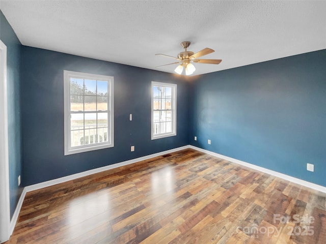 empty room with dark hardwood / wood-style flooring, ceiling fan, and a textured ceiling