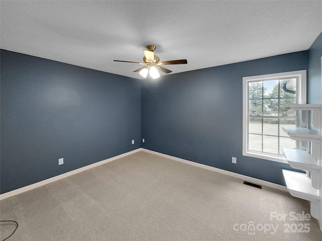 spare room with ceiling fan, a textured ceiling, and carpet