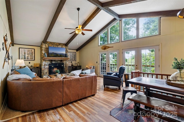 living room featuring beam ceiling, a fireplace, french doors, and light wood-type flooring