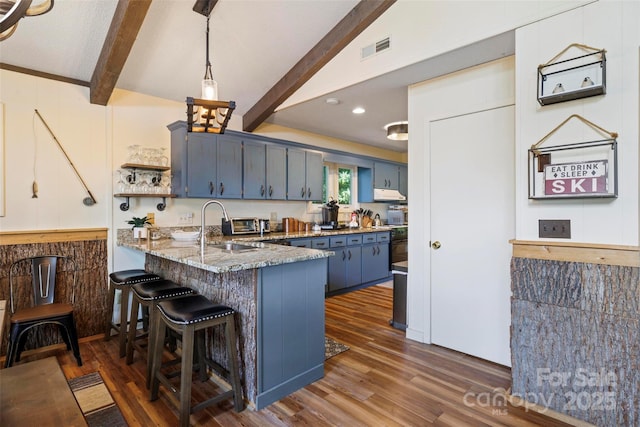 kitchen with blue cabinetry, sink, decorative light fixtures, dark hardwood / wood-style flooring, and kitchen peninsula