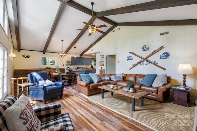 living room with wood-type flooring, vaulted ceiling with beams, and ceiling fan with notable chandelier