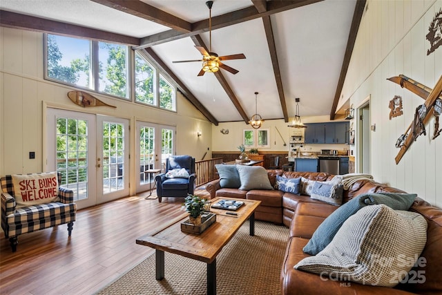 living room featuring ceiling fan with notable chandelier, high vaulted ceiling, hardwood / wood-style flooring, beam ceiling, and french doors