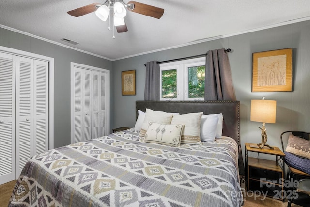 bedroom featuring multiple closets, crown molding, a textured ceiling, and ceiling fan