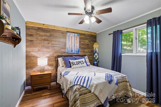 bedroom with crown molding, ceiling fan, dark hardwood / wood-style floors, a textured ceiling, and wood walls