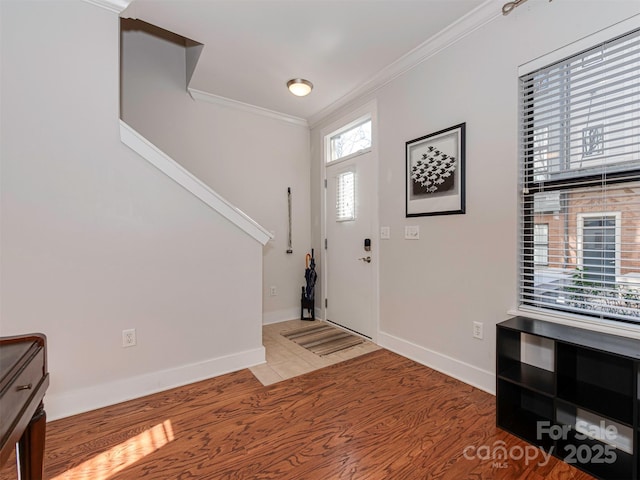 entryway with ornamental molding and light hardwood / wood-style flooring