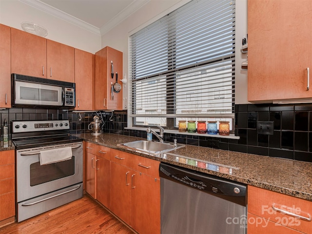 kitchen with sink, crown molding, tasteful backsplash, dark stone counters, and stainless steel appliances