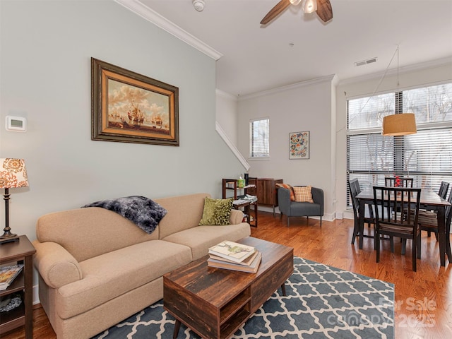 living room with hardwood / wood-style floors, crown molding, and ceiling fan