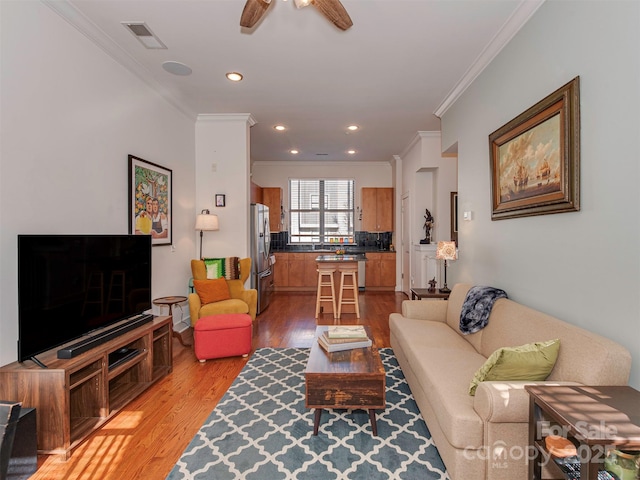 living room with crown molding, wood-type flooring, and ceiling fan