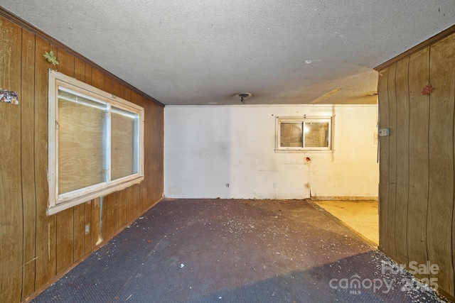 unfurnished room with a textured ceiling and wood walls