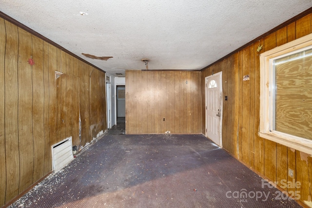 unfurnished room featuring dark carpet, a textured ceiling, and wood walls