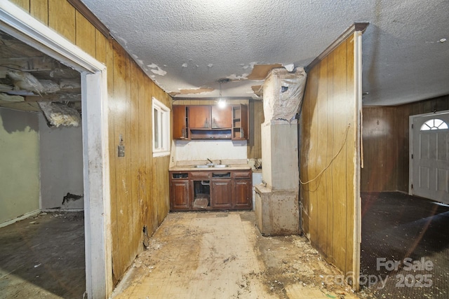 kitchen with wooden walls, sink, and a textured ceiling