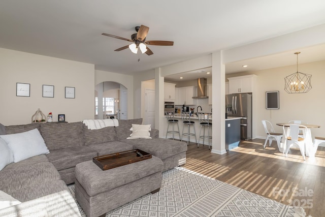 living room with sink, ceiling fan with notable chandelier, and dark hardwood / wood-style floors