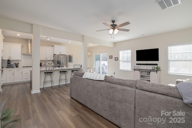 living room featuring ceiling fan, a healthy amount of sunlight, and dark hardwood / wood-style flooring