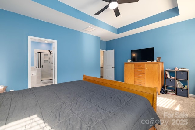 bedroom with ensuite bath, carpet floors, a raised ceiling, and ceiling fan