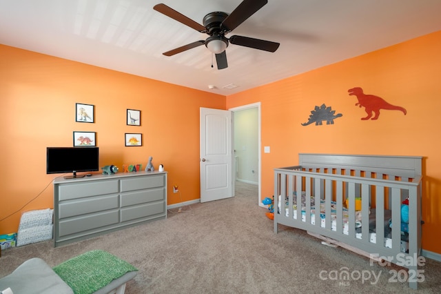 bedroom with ceiling fan, light colored carpet, and a crib