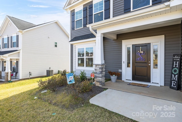 entrance to property with central AC unit and a yard