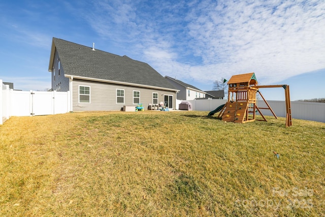 rear view of property featuring a playground and a lawn