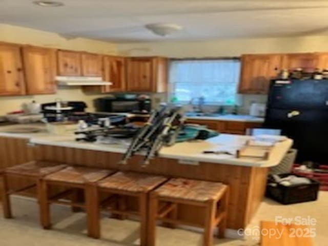 kitchen with black refrigerator, a kitchen bar, and kitchen peninsula