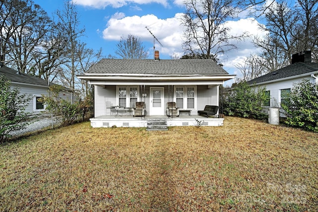 rear view of house featuring a porch and a yard