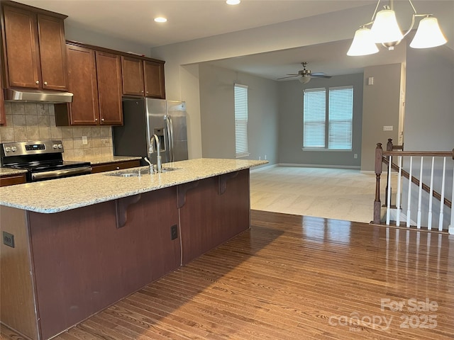 kitchen featuring decorative light fixtures, sink, backsplash, stainless steel appliances, and light wood-type flooring