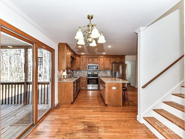 kitchen with pendant lighting, a breakfast bar area, stainless steel appliances, light stone countertops, and a kitchen island