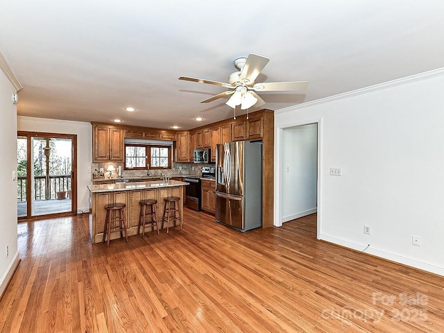 kitchen featuring a breakfast bar area, a center island, light hardwood / wood-style flooring, appliances with stainless steel finishes, and decorative backsplash