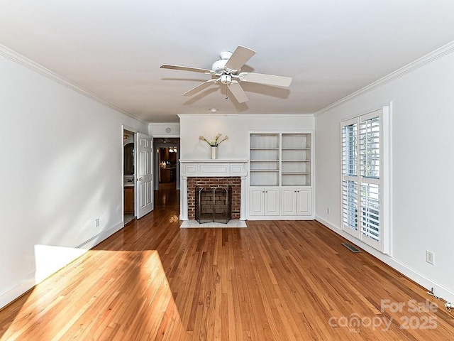 unfurnished living room featuring ornamental molding, a brick fireplace, hardwood / wood-style floors, and ceiling fan