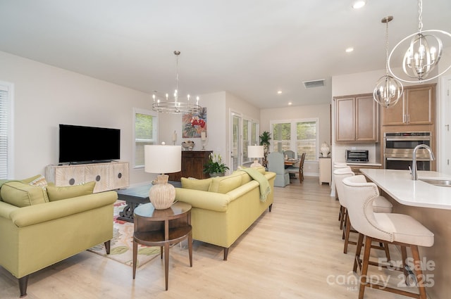 living room with light hardwood / wood-style floors, a chandelier, and sink