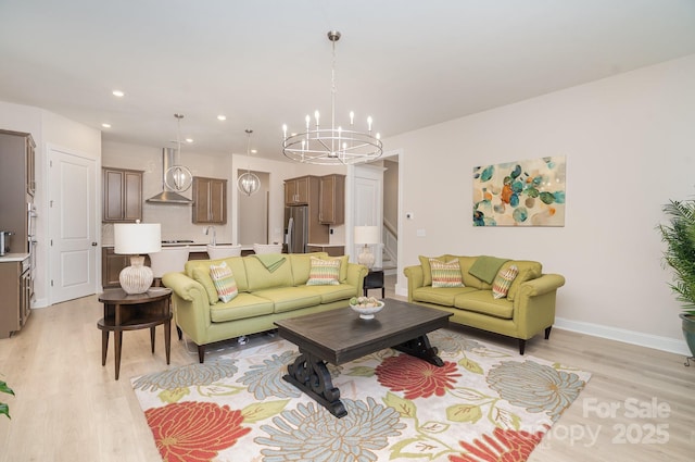 living room with an inviting chandelier, sink, and light hardwood / wood-style flooring