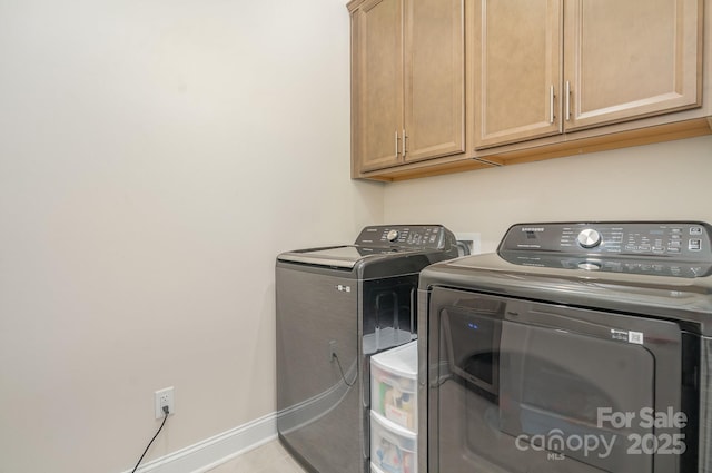 washroom featuring light tile patterned flooring, cabinets, and washer and clothes dryer