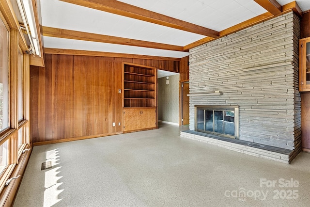 unfurnished living room featuring a stone fireplace, beamed ceiling, and wood walls