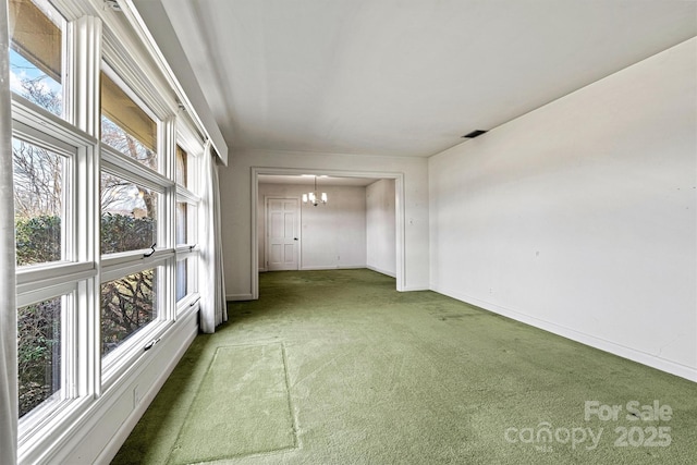 spare room with carpet flooring and a notable chandelier