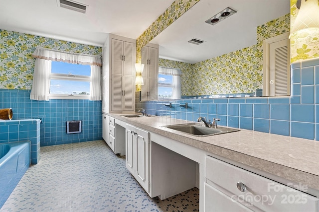 bathroom featuring tile walls, vanity, a bathtub, and a healthy amount of sunlight