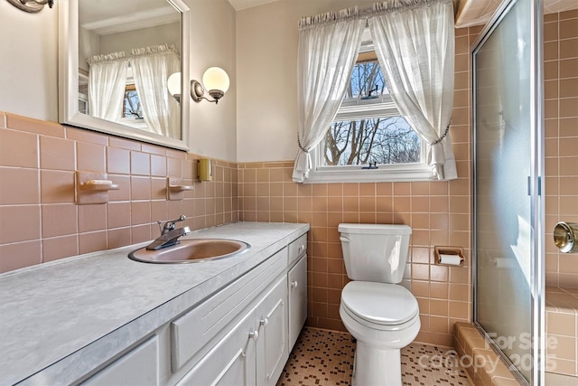 bathroom featuring vanity, tile walls, an enclosed shower, and toilet