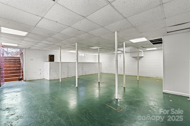 basement featuring a drop ceiling and electric panel