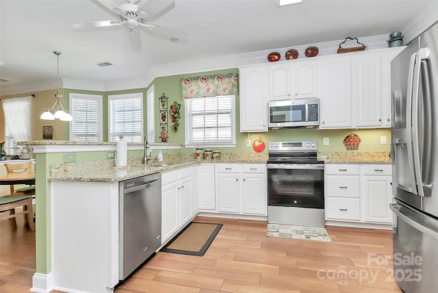 kitchen with pendant lighting, white cabinetry, appliances with stainless steel finishes, and crown molding