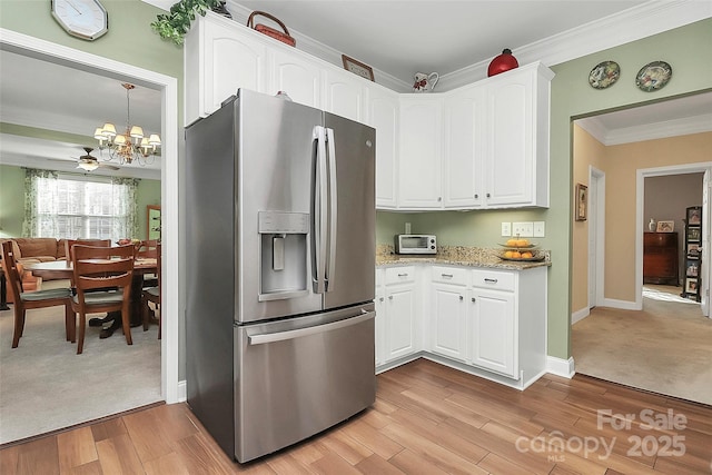 kitchen featuring white cabinets, light stone counters, stainless steel fridge with ice dispenser, crown molding, and light wood-type flooring