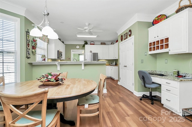 dining room with ornamental molding, light wood-type flooring, and plenty of natural light