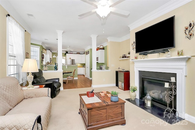 living room with decorative columns, crown molding, and ceiling fan