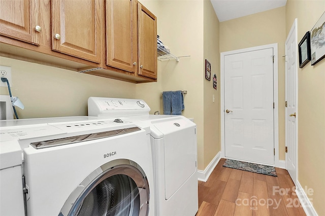 clothes washing area with light hardwood / wood-style floors, cabinets, and washing machine and clothes dryer