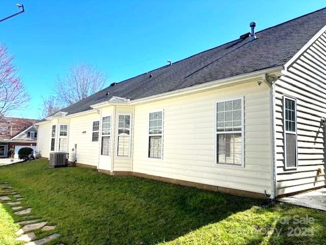 back of property featuring a lawn and central AC