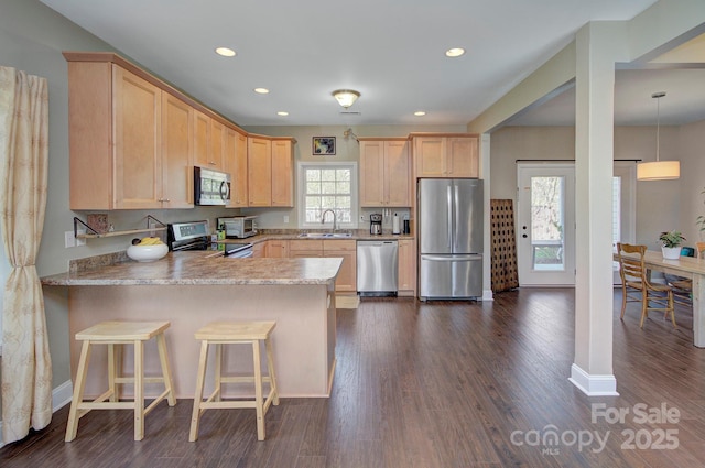 kitchen featuring pendant lighting, light brown cabinetry, sink, kitchen peninsula, and stainless steel appliances