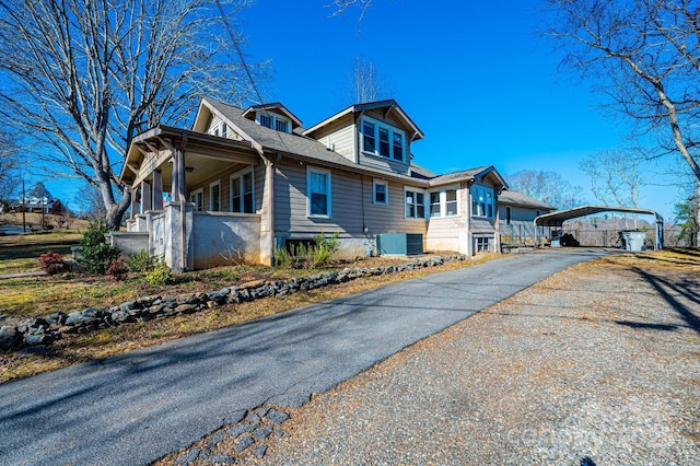 view of side of property with a carport, central AC unit, and covered porch