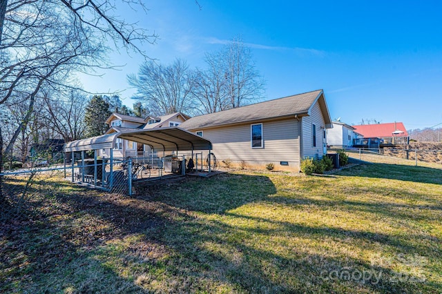 rear view of property featuring a carport, central AC unit, and a lawn