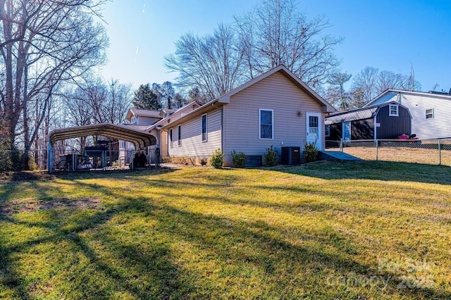 back of property with a carport, central AC unit, and a lawn