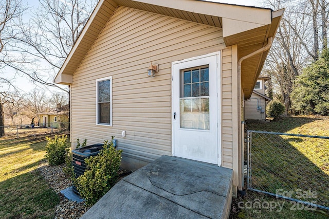 view of exterior entry featuring a yard and central AC unit