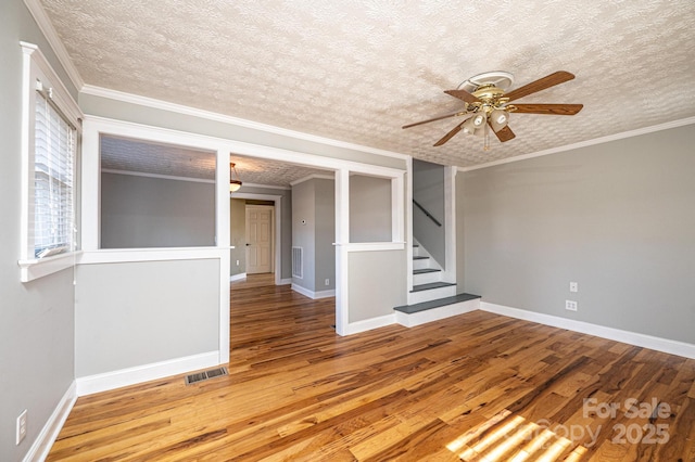 unfurnished room featuring ceiling fan, hardwood / wood-style flooring, ornamental molding, and a textured ceiling