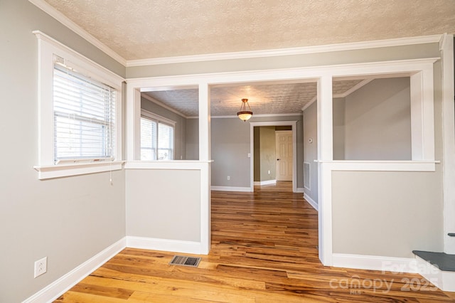 unfurnished room with hardwood / wood-style floors, crown molding, and a textured ceiling