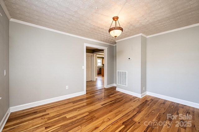 empty room featuring hardwood / wood-style flooring, ornamental molding, and a textured ceiling