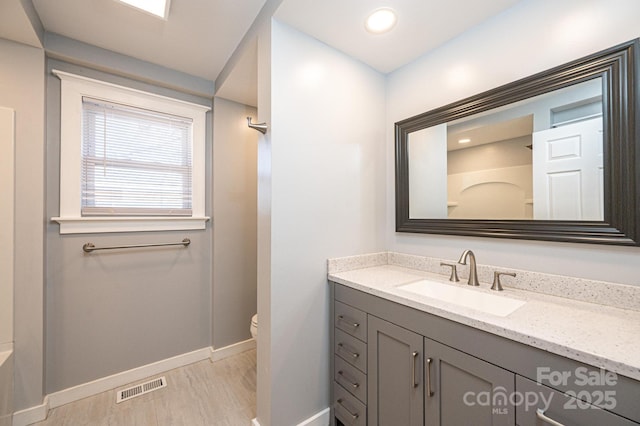 bathroom with hardwood / wood-style flooring, vanity, toilet, and a shower